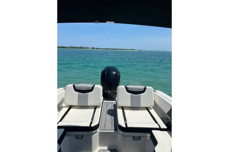 Slide: The Image of 2024 Chaparral 250 OSX boat interior with ocean view, featuring comfortable seating and outboard motor. - 16