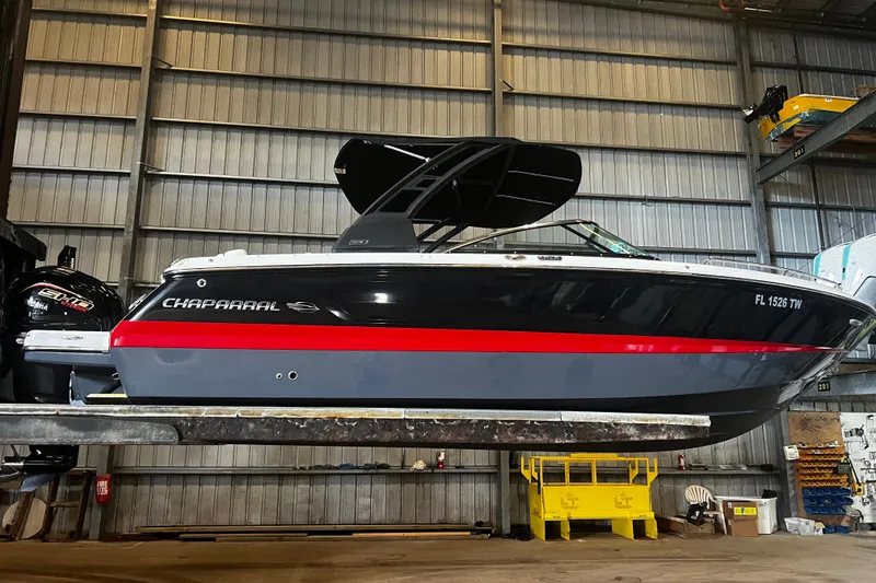 Slide: The Image of 2024 Chaparral 250 OSX boat in a warehouse, featuring sleek black and red design. - 11