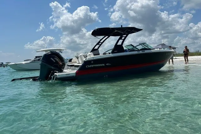 Slide: The Image of 2024 Chaparral 250 OSX boat anchored on clear water near a sandy beach. - 3