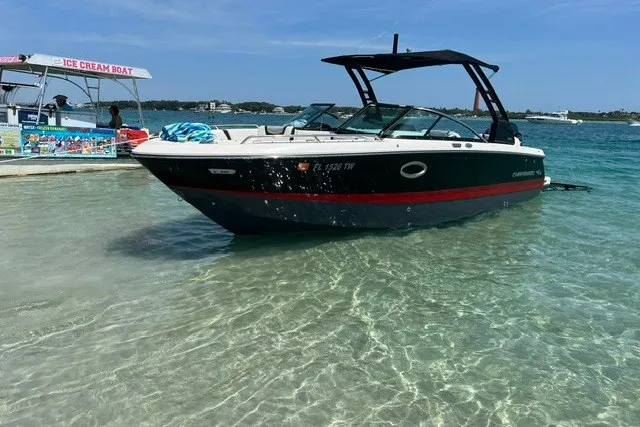 Slide: The Image of 2024 Chaparral 250 OSX boat anchored in clear shallow water near an ice cream boat. - 7