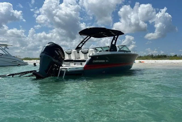 Slide: The Image of 2024 Chaparral 250 OSX boat anchored in clear water under a cloudy sky. - 4