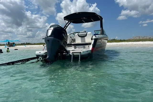 Slide: The Image of 2024 Chaparral 250 OSX boat anchored in clear water near a sandy beach. - 5