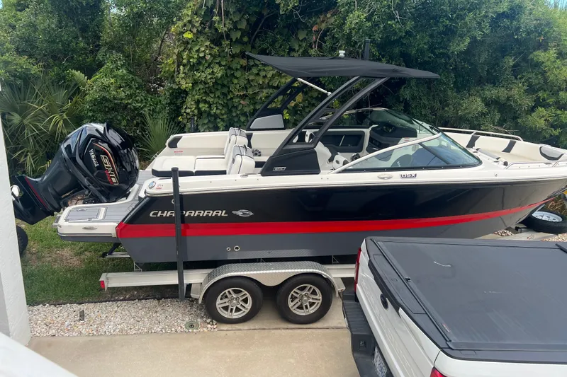 Slide: The Image of 2024 Chaparral 250 OSX boat on trailer, black and red design, parked outdoors. - 12