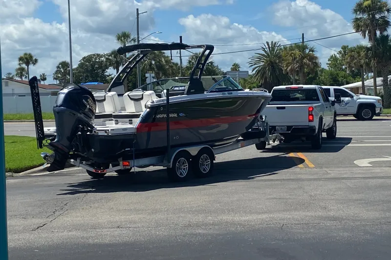 Slide: The Image of 2024 Chaparral 250 OSX boat on trailer, towed by a white truck on a sunny day. - 13