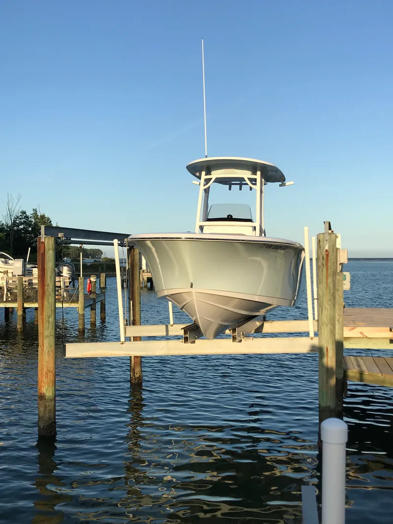 Slide: The Image of A 2021 Sportsman Open 232 Center Console boat on a lift by the water. - 1