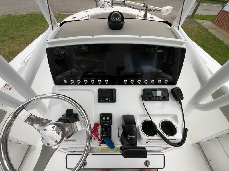 Slide: The Image of The image shows the helm of a 2021 Sportsman Open 232 Center Console boat. It features a modern dashboard with a large screen, compass, radio, and various controls. The helm is clean and well-organized. - 16