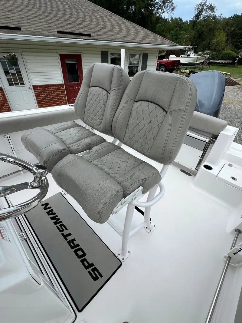 Slide: The Image of Two cushioned seats on a Sportsman Open 232 Center Console boat, with a steering wheel in front. - 24