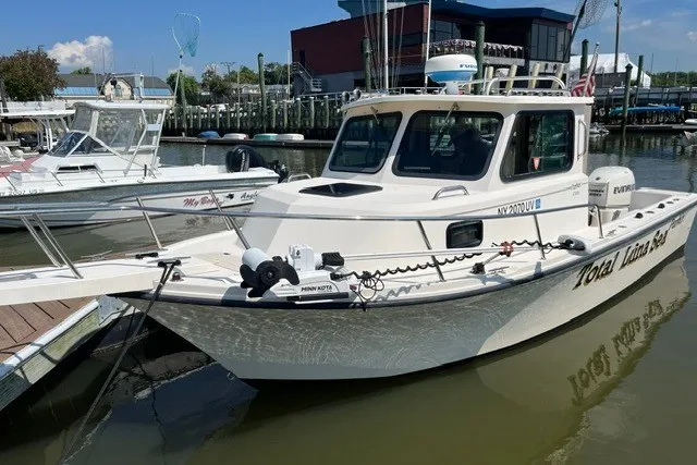 The Image of 2001 Parker 2320 Sport Cabin boat docked at a marina, featuring a sleek white design. - 1