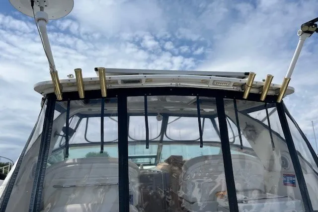 Slide: The Image of 2001 Sea Ray 340 Amberjack boat with clear canopy and fishing rod holders under a blue sky. - 2
