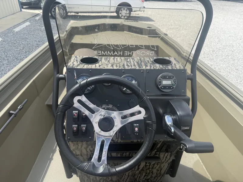 Slide: The Image of The image shows the helm of a Thor Lake Hammer 1900 CC LOW DECK boat. It features a modern steering wheel, gauges, and controls. - 7