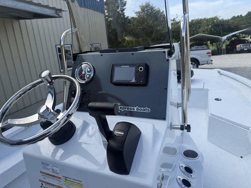 Slide: The Image of The image shows the helm of an Xpress Hyper-Lift Bay Series H22B-175 SHO boat. It features a steering wheel, controls, and a display. Trees and a building are visible in the background. - 4