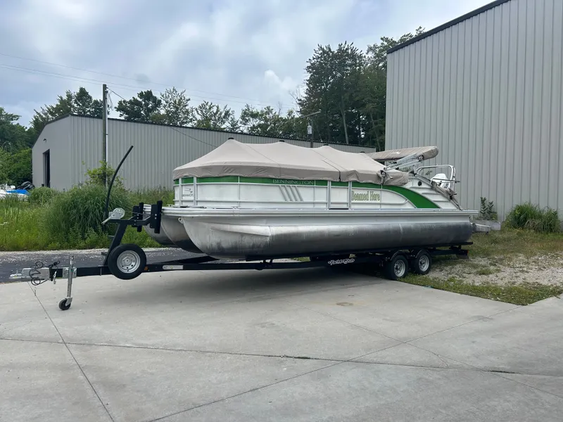 Slide: The Image of A 2021 Bennington 23LSBSD pontoon boat on a trailer, parked outside a warehouse. - 17