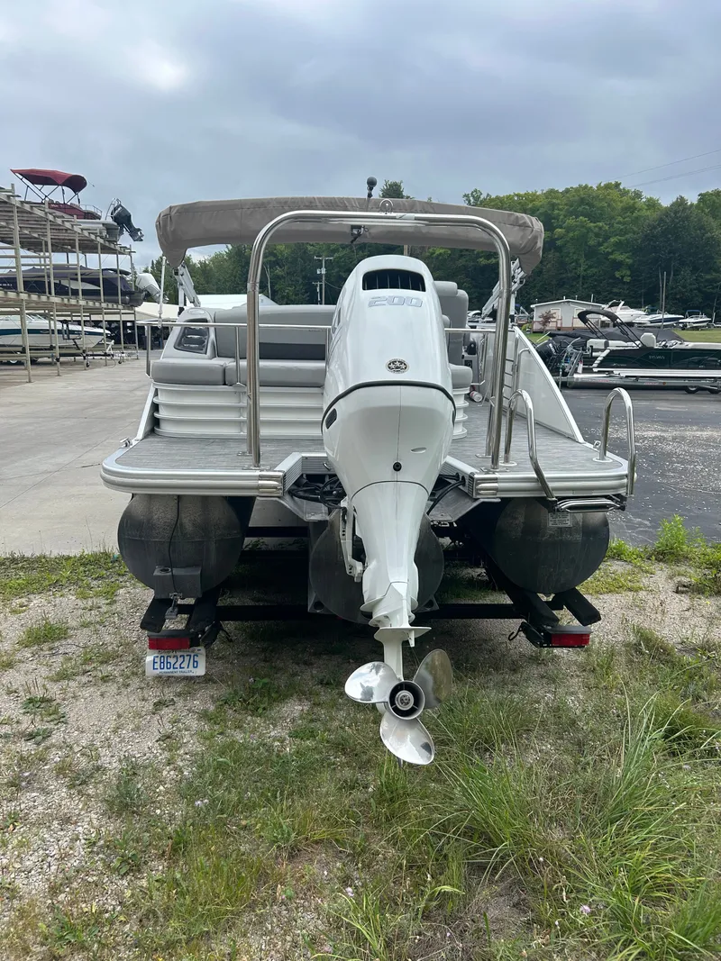 Slide: The Image of A 2021 Bennington 23LSBSD pontoon boat with an outboard motor, parked on a trailer. - 5