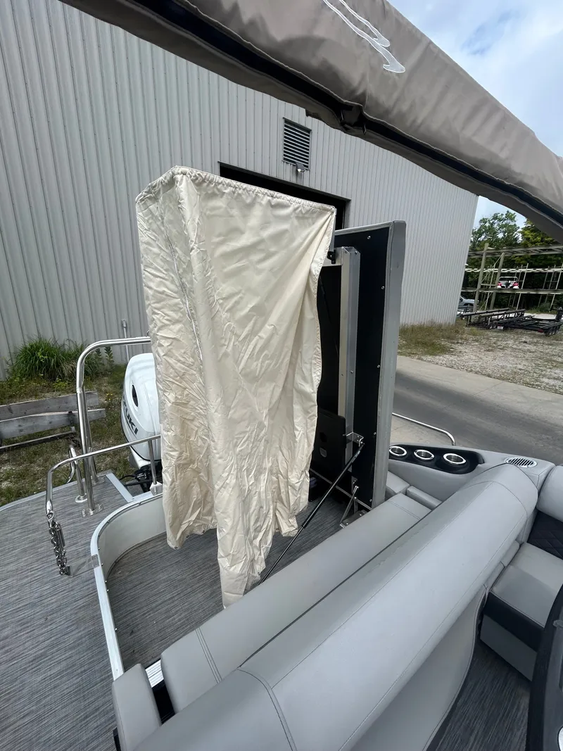 Slide: The Image of The image shows the rear of a 2021 Bennington 23LSBSD pontoon boat with gray upholstery and an engine. - 16