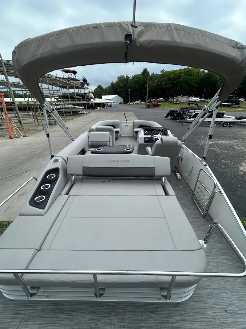 Slide: The Image of A 2021 Bennington 23LSBSD pontoon boat with gray upholstery and a Bimini top, parked on a lot. - 15