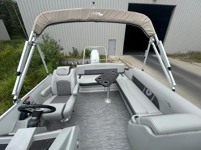 Slide: The Image of The image shows the interior of a 2021 Bennington 23LSBSD pontoon boat with gray seating and a table. - 13