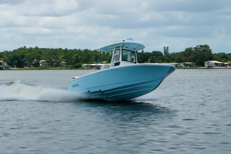 Slide: The Image of 2027 Pathfinder 2800 Hybrid boat cruising on a lake with scenic background. - 18