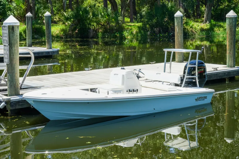 Slide: The Image of 2027 Hewes Redfisher 16 boat docked on calm water, surrounded by lush greenery. - 31