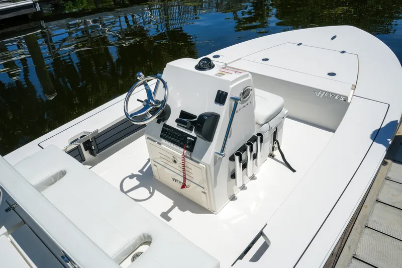 Slide: The Image of 2027 Hewes Redfisher 16 boat interior with steering console and seating, docked by water. - 23