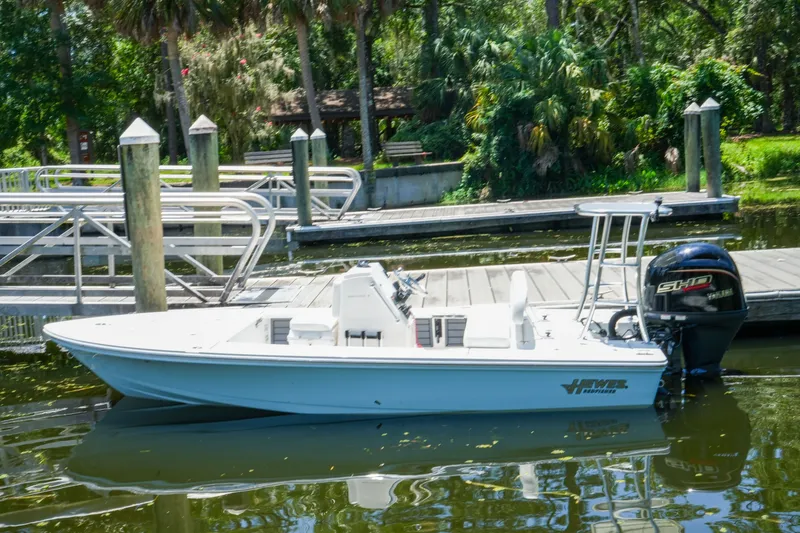 Slide: The Image of 2027 Hewes Redfisher 16 boat docked on a calm river with lush greenery. - 32