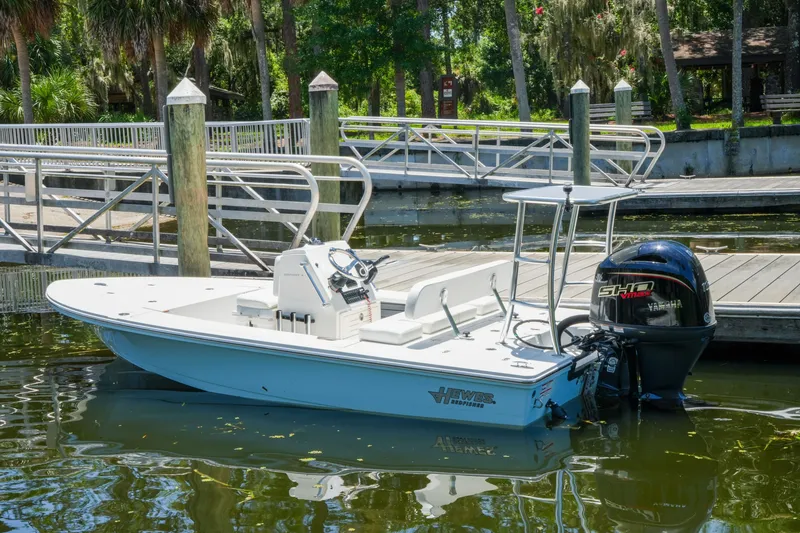 Slide: The Image of 2027 Hewes Redfisher 16 boat docked at a marina with lush greenery. - 34