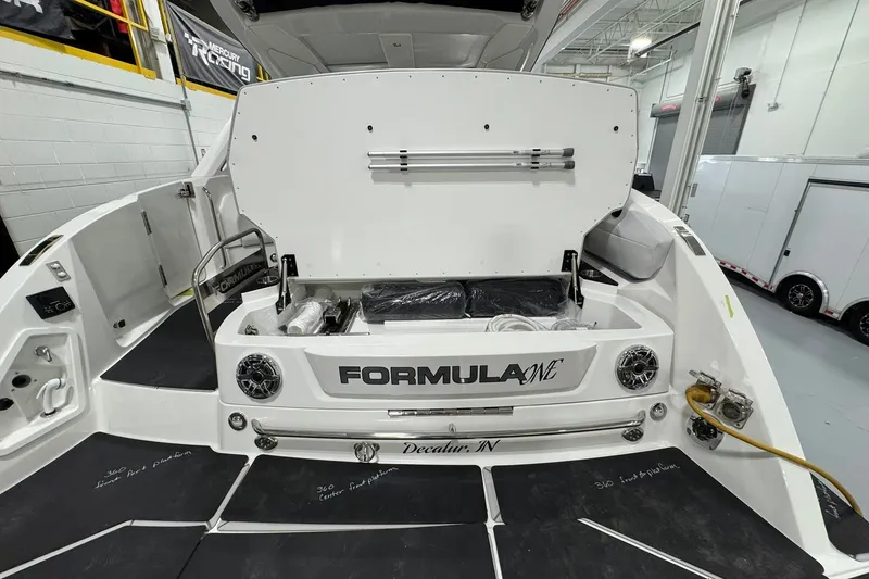 Slide: The Image of 2026 Formula 360 Crossover Bowrider I/O boat with open storage compartment in a showroom. - 21
