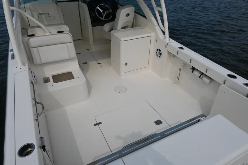 Slide: The Image of 2014 Pursuit DC 265 Dual Console boat interior with seating and steering wheel on water. - 30