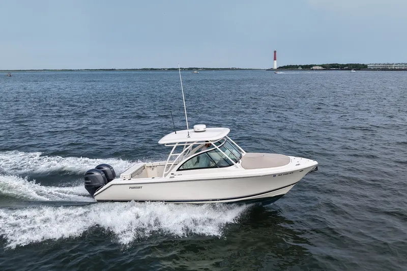 Slide: The Image of 2014 Pursuit DC 265 Dual Console boat cruising on open water near a lighthouse. - 14