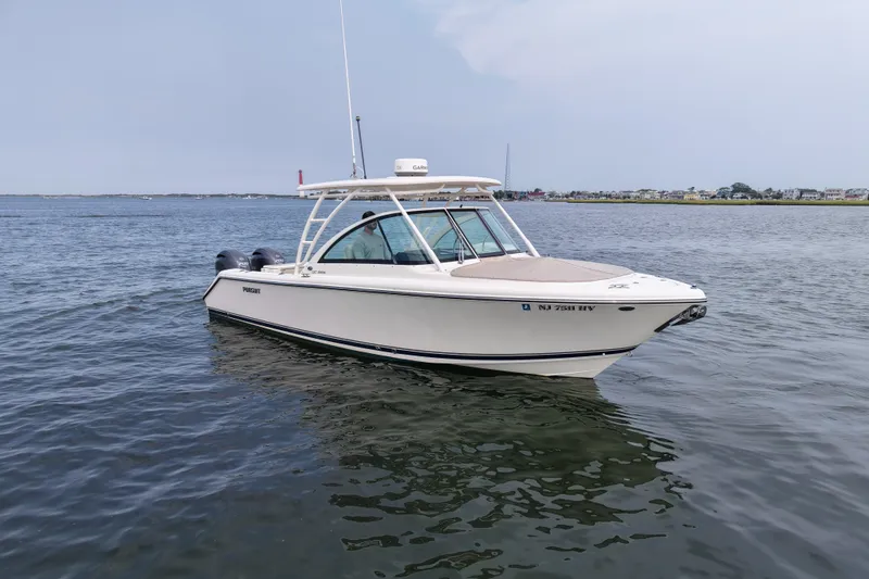 Slide: The Image of 2014 Pursuit DC 265 Dual Console boat on calm water, distant shoreline visible. - 1