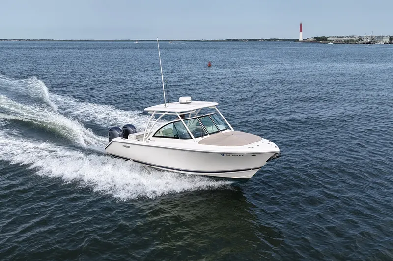 Slide: The Image of 2014 Pursuit DC 265 Dual Console boat cruising on open water near a lighthouse. - 16