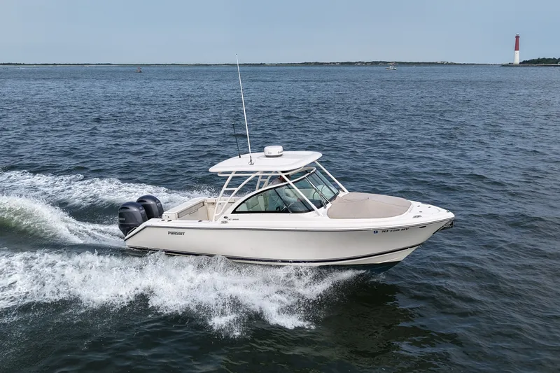 Slide: The Image of 2014 Pursuit DC 265 Dual Console boat cruising on open water near a lighthouse. - 13
