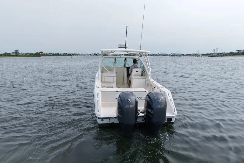 Slide: The Image of 2014 Pursuit DC 265 Dual Console boat on water, rear view with twin engines. - 3