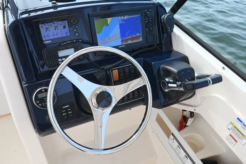 Slide: The Image of 2014 Pursuit DC 265 Dual Console boat dashboard with steering wheel and navigation controls. - 21