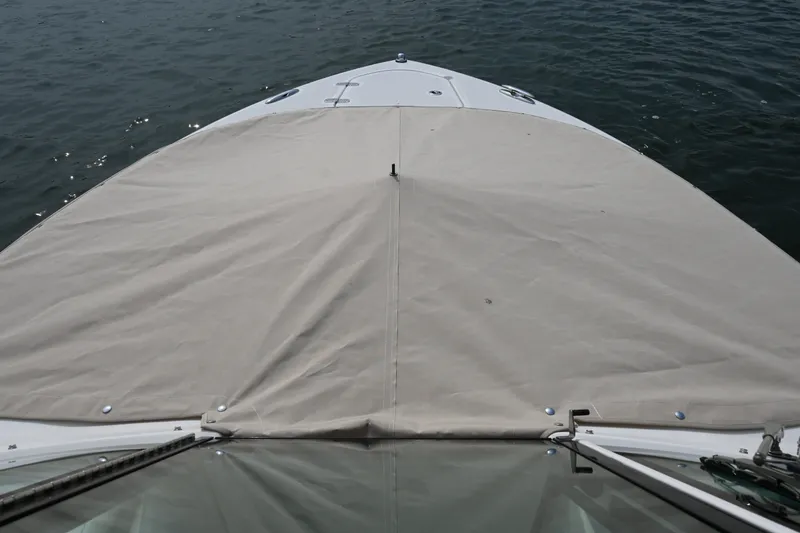 Slide: The Image of 2014 Pursuit DC 265 Dual Console boat with beige cover on water. - 31