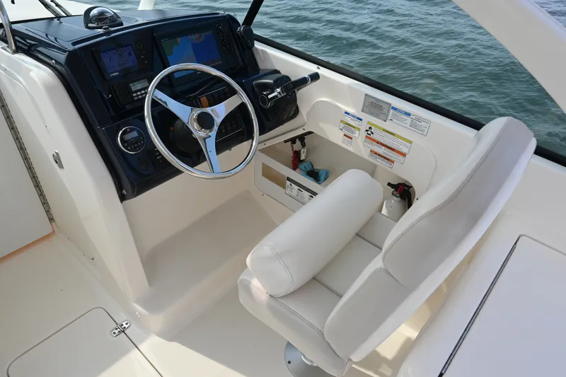 Slide: The Image of 2014 Pursuit DC 265 Dual Console boat cockpit with steering wheel and navigation controls. - 20