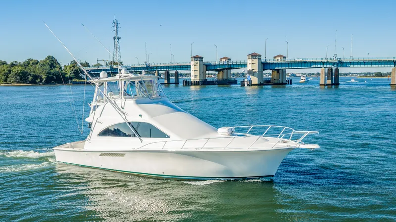 The Image of A white yacht cruises on a river, with a bridge in the background. - 0