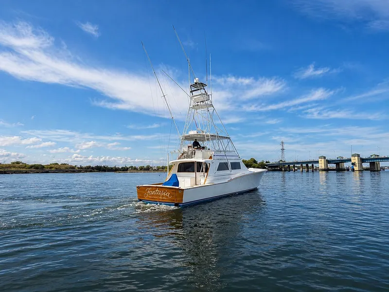 Slide: The Image of A 1995 Jim Smith 65 Convertible boat cruising on calm water under a blue sky. - 3