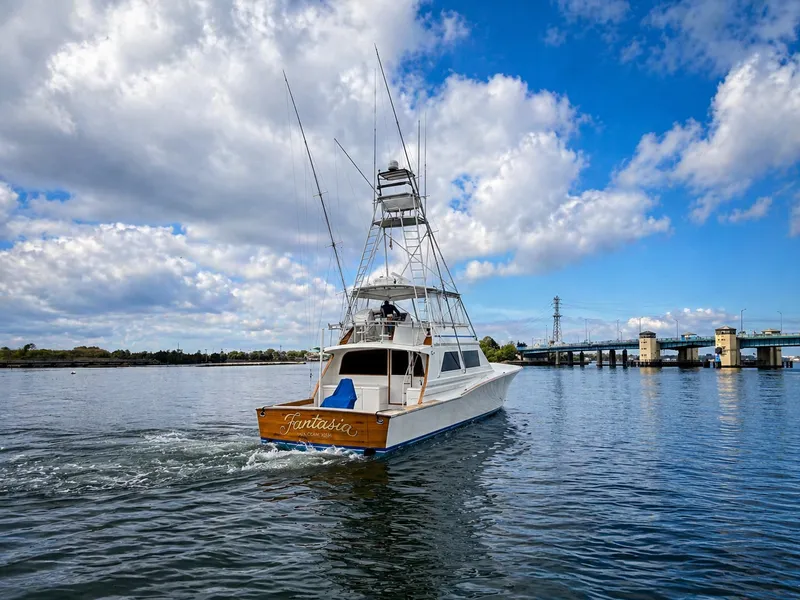 Slide: The Image of A 1995 Jim Smith 65 Convertible boat cruising on calm water under a cloudy sky. - 4