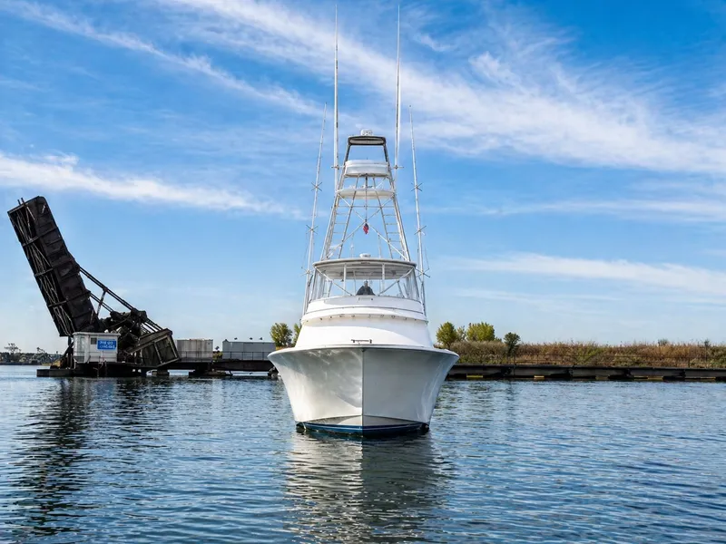 Slide: The Image of A 1995 Jim Smith 65 Convertible boat on calm water in front of an open bridge. - 8
