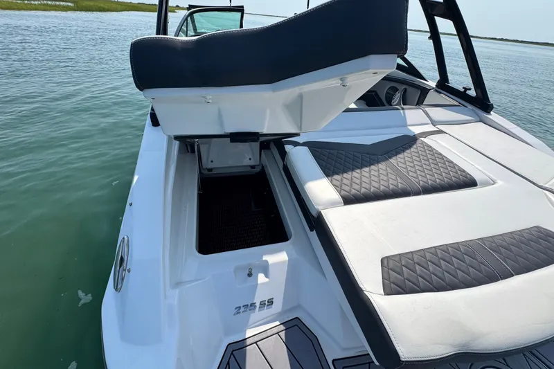 Slide: The Image of 2023 Monterey 235SS Super Sport boat with open storage compartment on calm water. - 11