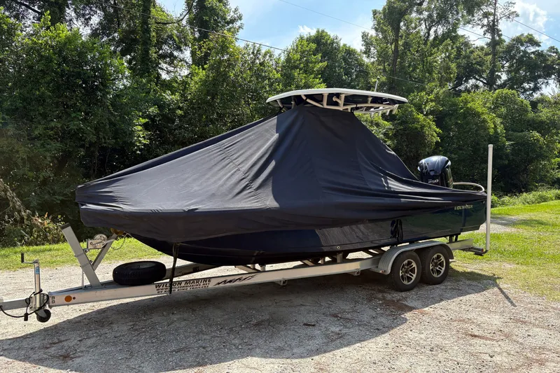 Slide: The Image of 2019 Tidewater 2200 Carolina Bay boat covered on trailer, surrounded by greenery. - 44