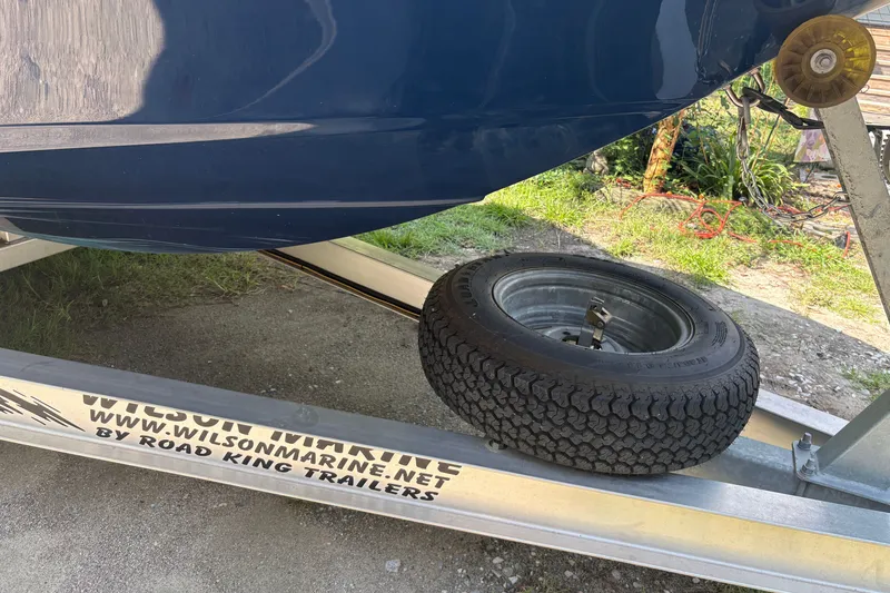 Slide: The Image of Trailer with 2019 Tidewater 2200 Carolina Bay boat, featuring spare tire and Wilson Marine branding. - 43