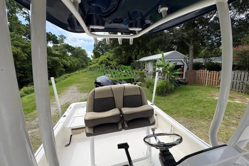 Slide: The Image of 2019 Tidewater 2200 Carolina Bay boat interior with seating and steering wheel, parked outdoors. - 30