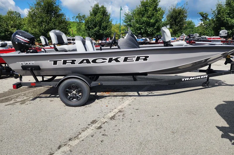 The Image of 2027 Tracker Pro Team 175 boat on trailer, parked outdoors, with trees in background. - 0