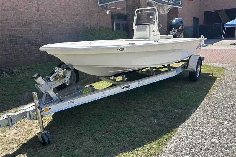 Slide: The Image of 2026 Mako 18 Pro Skiff on trailer, parked outdoors near brick building. - 2