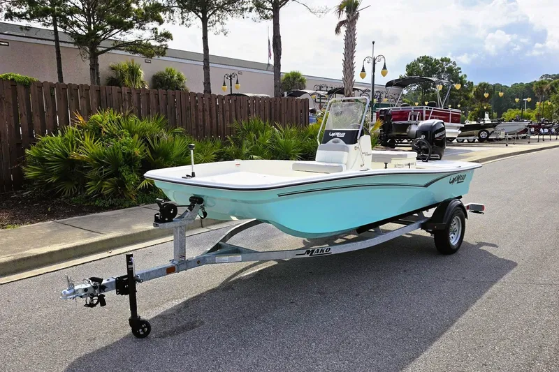 Slide: The Image of 2026 Mako Pro Skiff 15 CC boat on trailer, parked outdoors near greenery. - 12