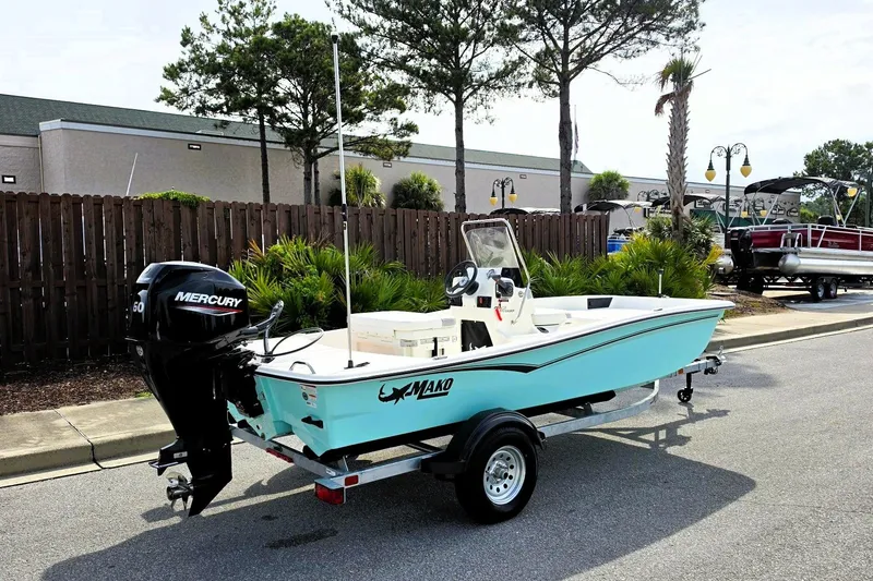 Slide: The Image of 2026 Mako Pro Skiff 15 CC boat on trailer, parked outdoors near palm trees. - 2