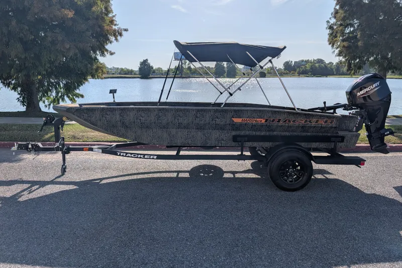 The Image of 2027 Tracker Grizzly 1756 T Marsh boat on trailer by a lake. - 0