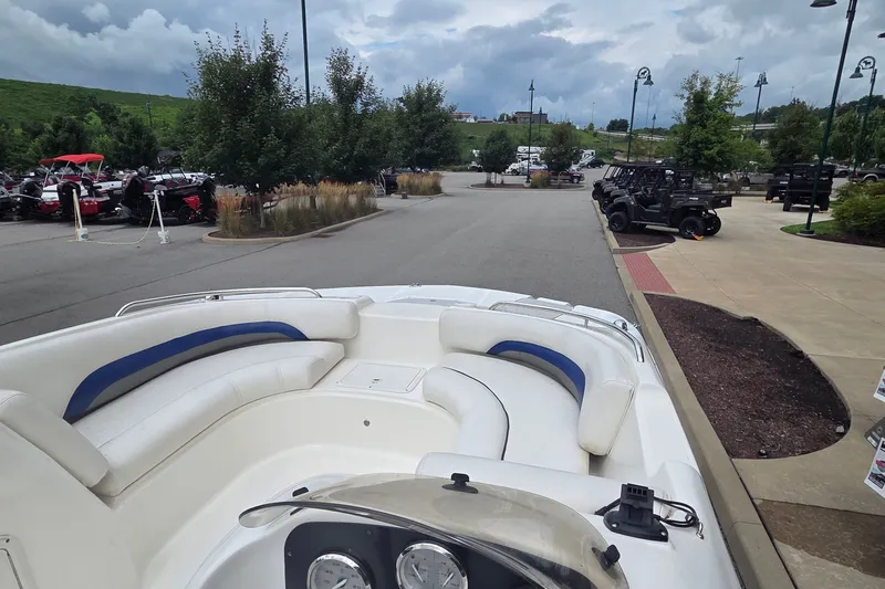 Slide: The Image of 2011 Hurricane SunDeck Sport 188 OB boat parked, showcasing spacious seating and dashboard, under cloudy skies. - 9