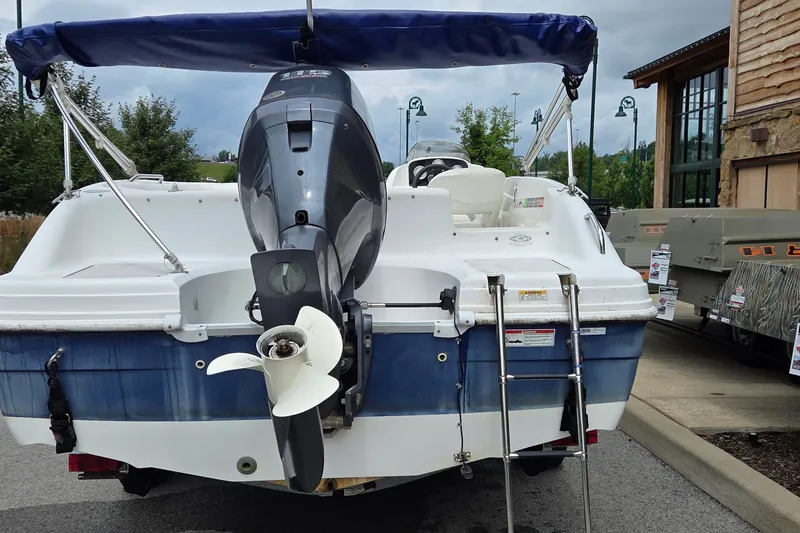 Slide: The Image of 2011 Hurricane SunDeck Sport 188 OB boat with outboard motor and ladder, parked outdoors. - 8